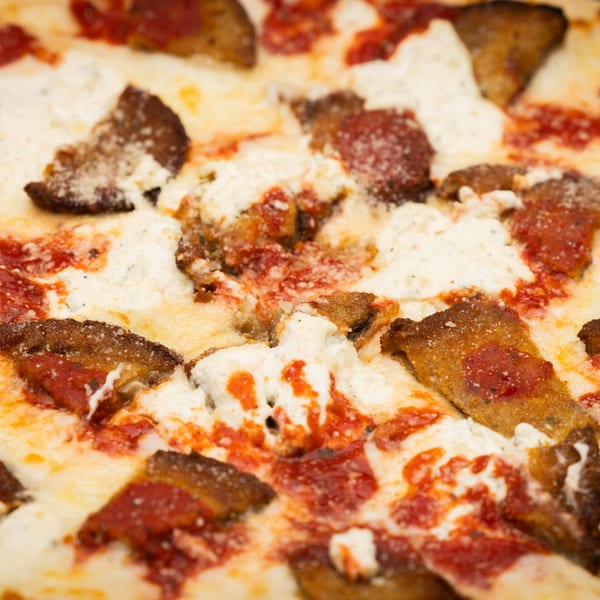 Close-up of I Love NY Pizza's Sicilian pizza with ricotta cheese, tomato sauce, and crispy crust.